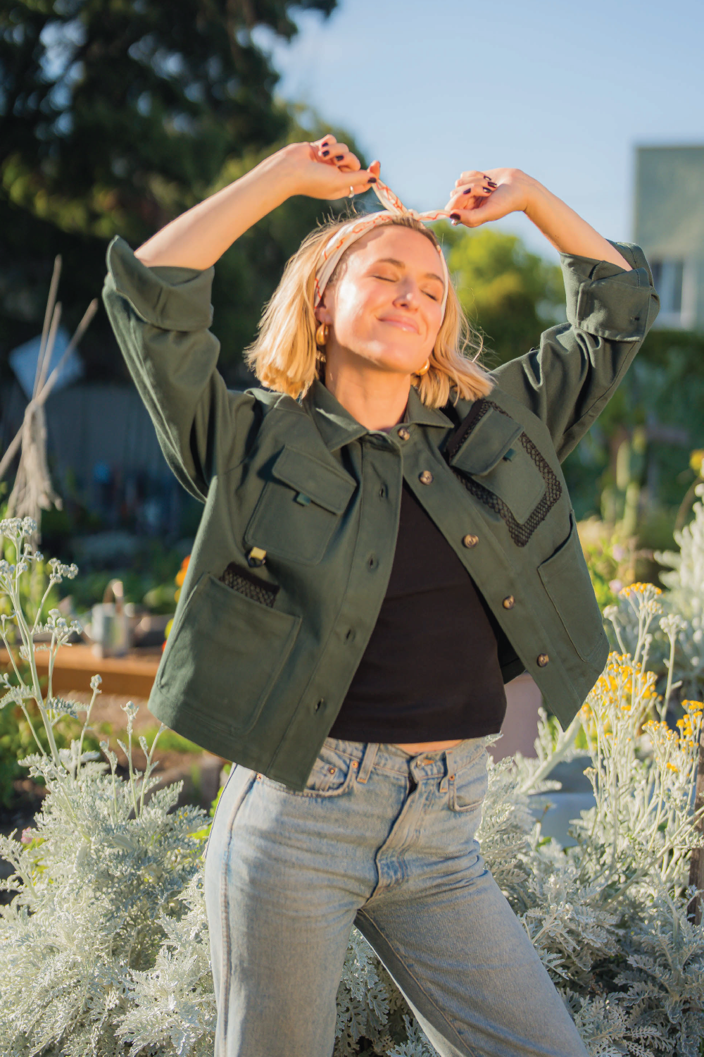 Blonde woman wearing forest green long sleeve denim jacket with 4 front pockets denim Levis jeans and head scarf