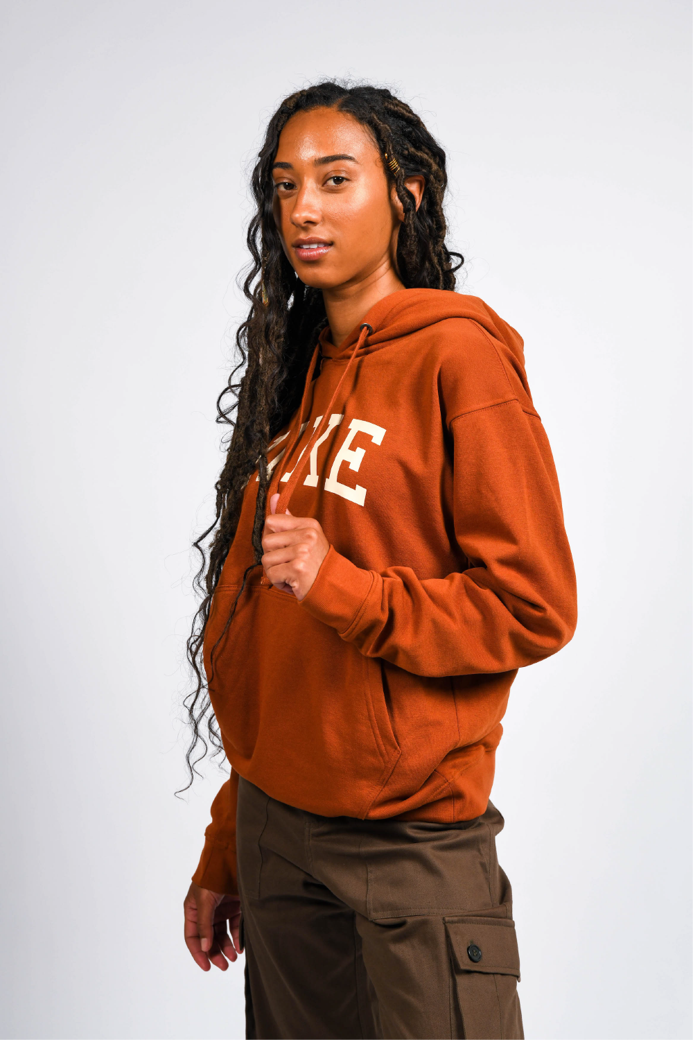 black woman in orange pullover outdoor hoodie with pockets #color_rust brown