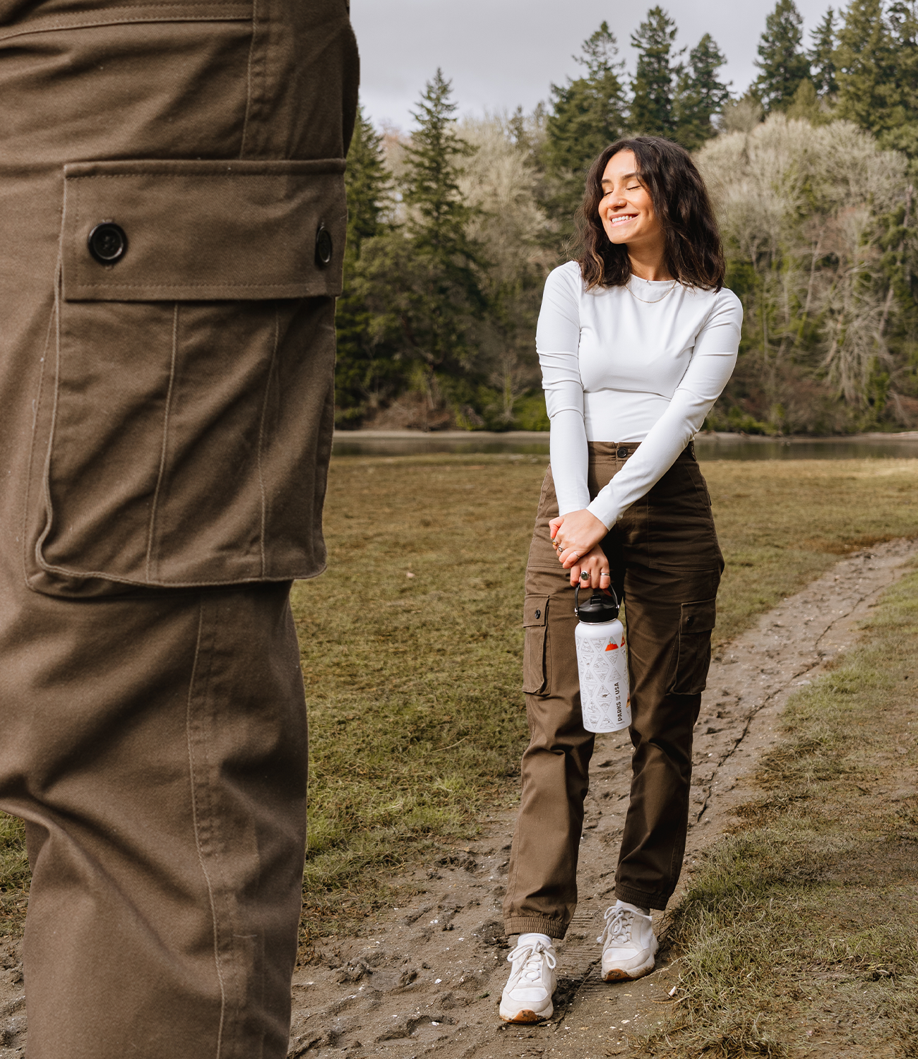 Brown cargo pant pocket on left and woman hiking in brown cargo pants and white travel water bottle