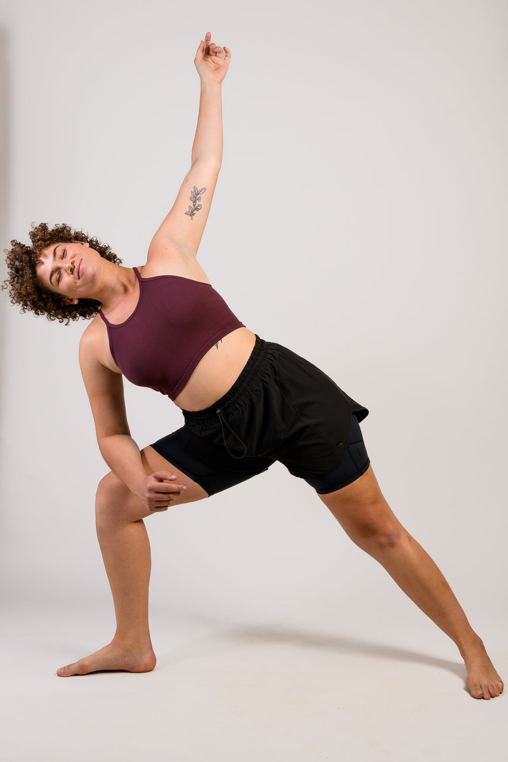 tall woman stretching in black workout running track shorts with tank top #color_black