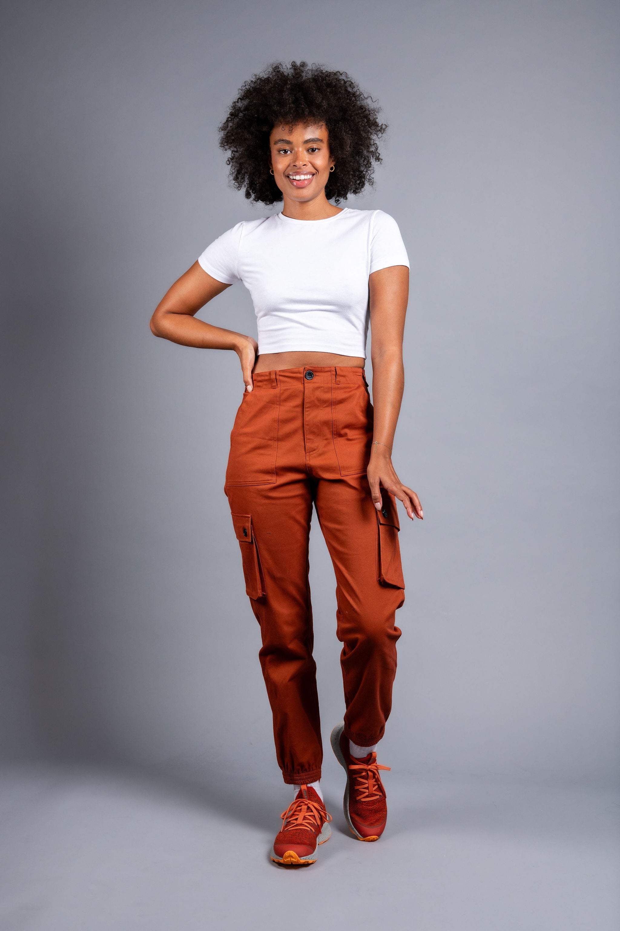 woman in adjustable orange cargo hiking pants and tee shirt #color_burnt Sienna
