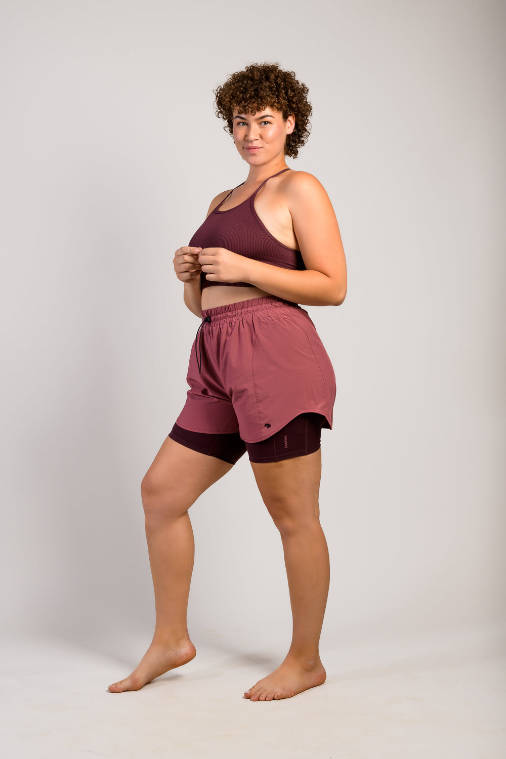 #color_dusty rose/mauve _tall plus size woman in burgundy pink lightweight running shorts and biker shorts with side pocket