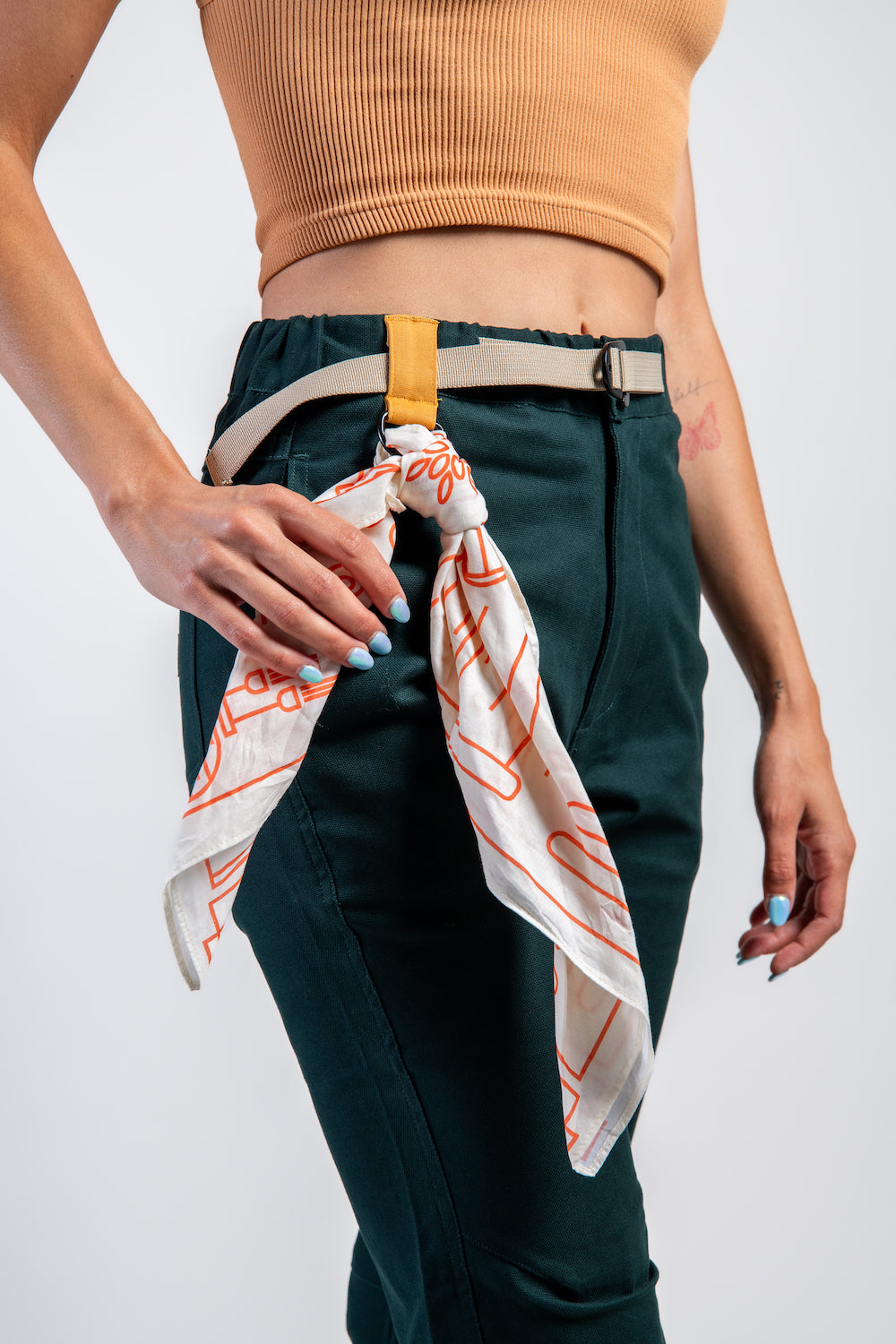 Woman in casual straight leg pants and orange tank top and neck scarf #color_emerald