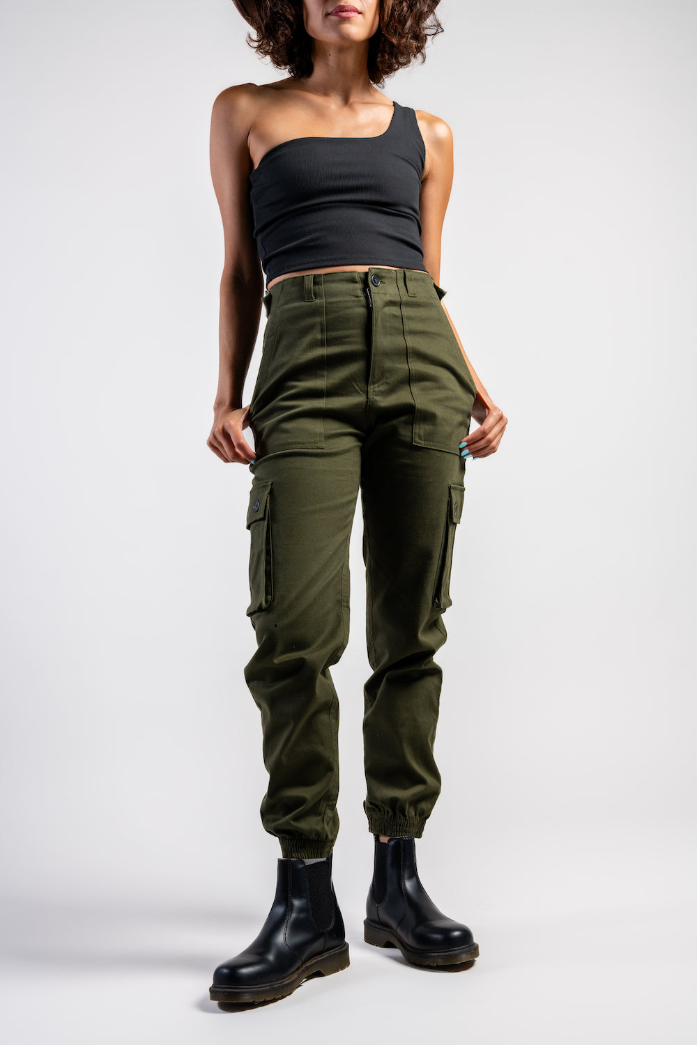 woman in army green cargo outdoor hiking camping pants and asymmetrical black top #color_forest