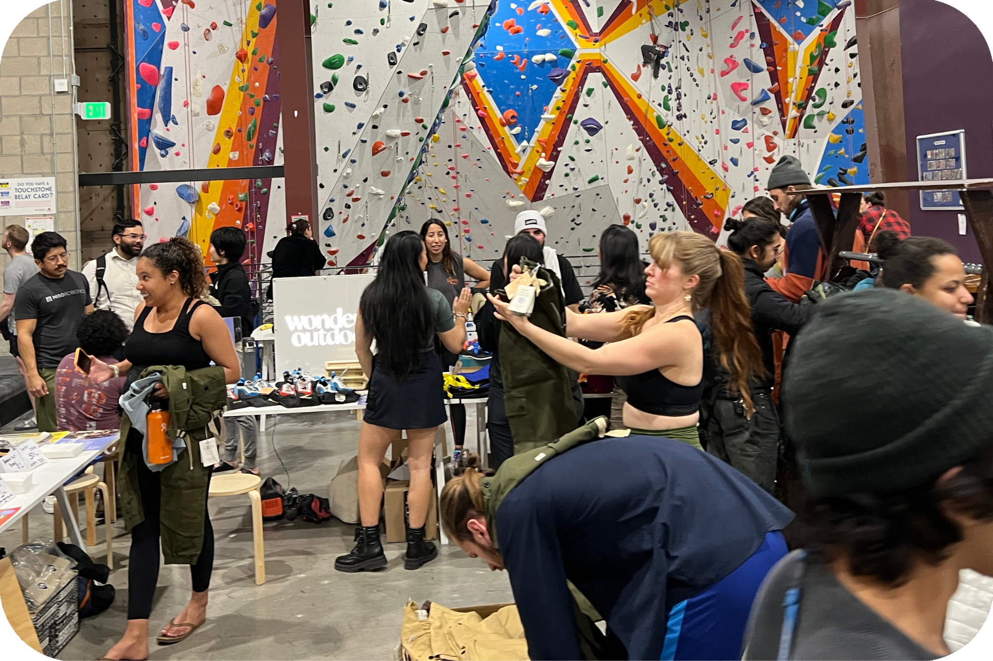 Men and women gathering at climbing gym for garage and bake sale event