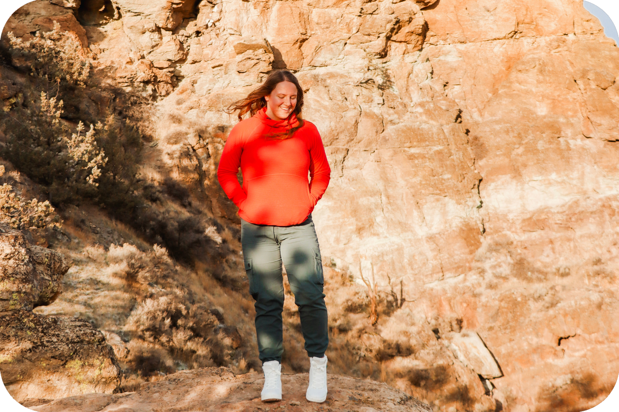 Woman standing in front of red rocks on a hiking trail