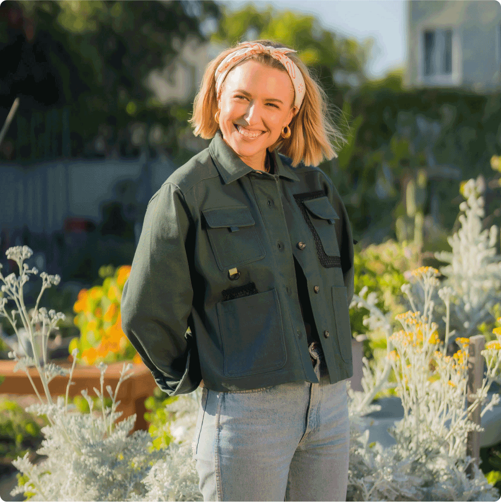 woman with short blonde hair standing in garden wearing green cargo denim jacket and levis jeans
