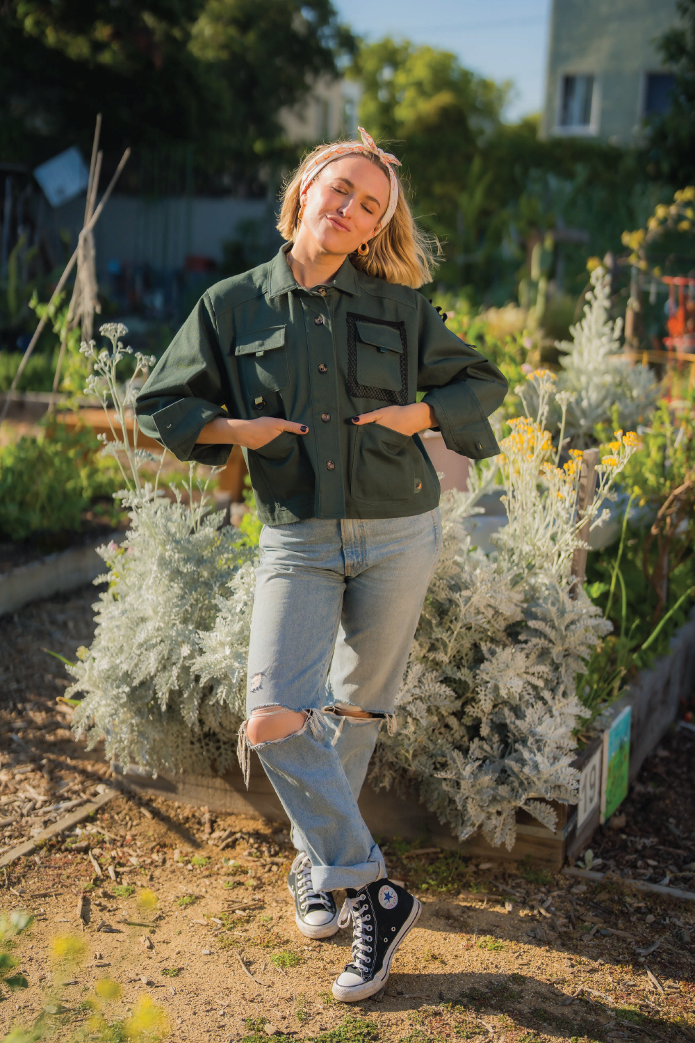 Blonde woman wearing forest green long sleeve denim jacket with 4 front pockets denim Levis jeans and head scarf and black converse originals