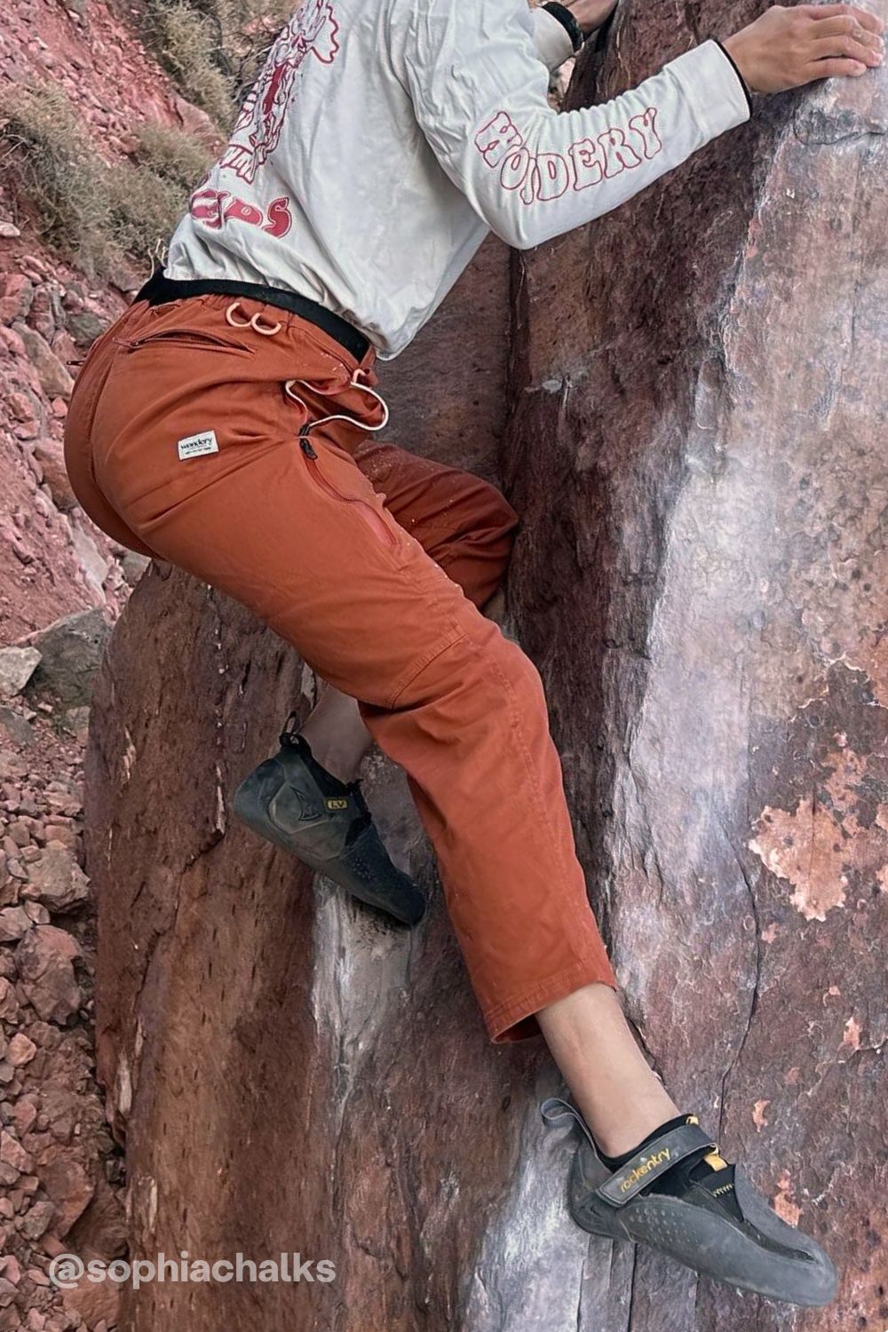 woman in adjustable orange climbing pants and tee shirt #color_red rocks