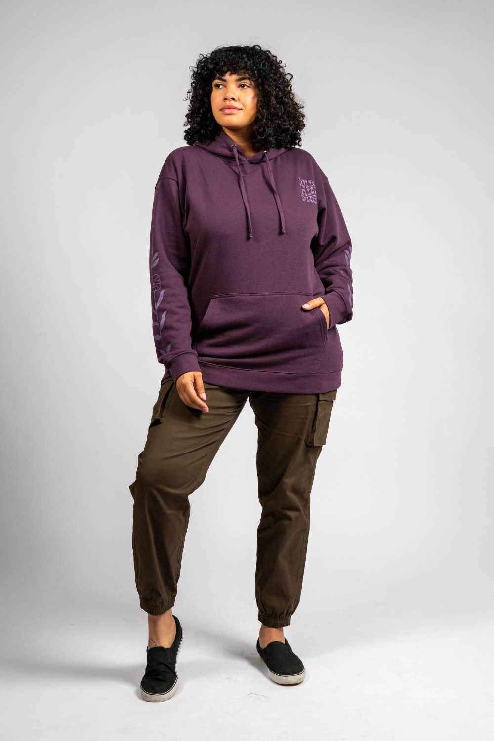 Tall woman in purple long sleeve pullover graphic hoodie and cargo pants #color_plum