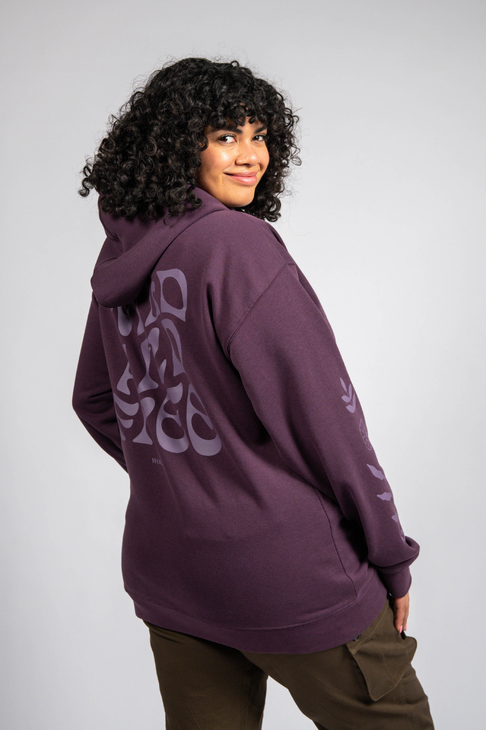 Tall woman in purple long sleeve pullover graphic hoodie and cargo pants #color_plum