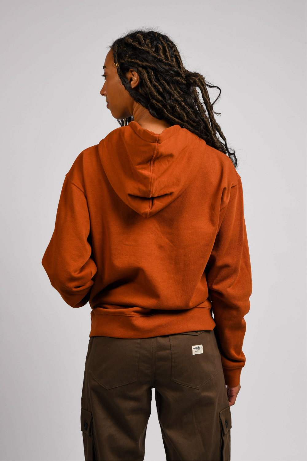 black woman in orange pullover outdoor hoodie with pockets #color_rust brown