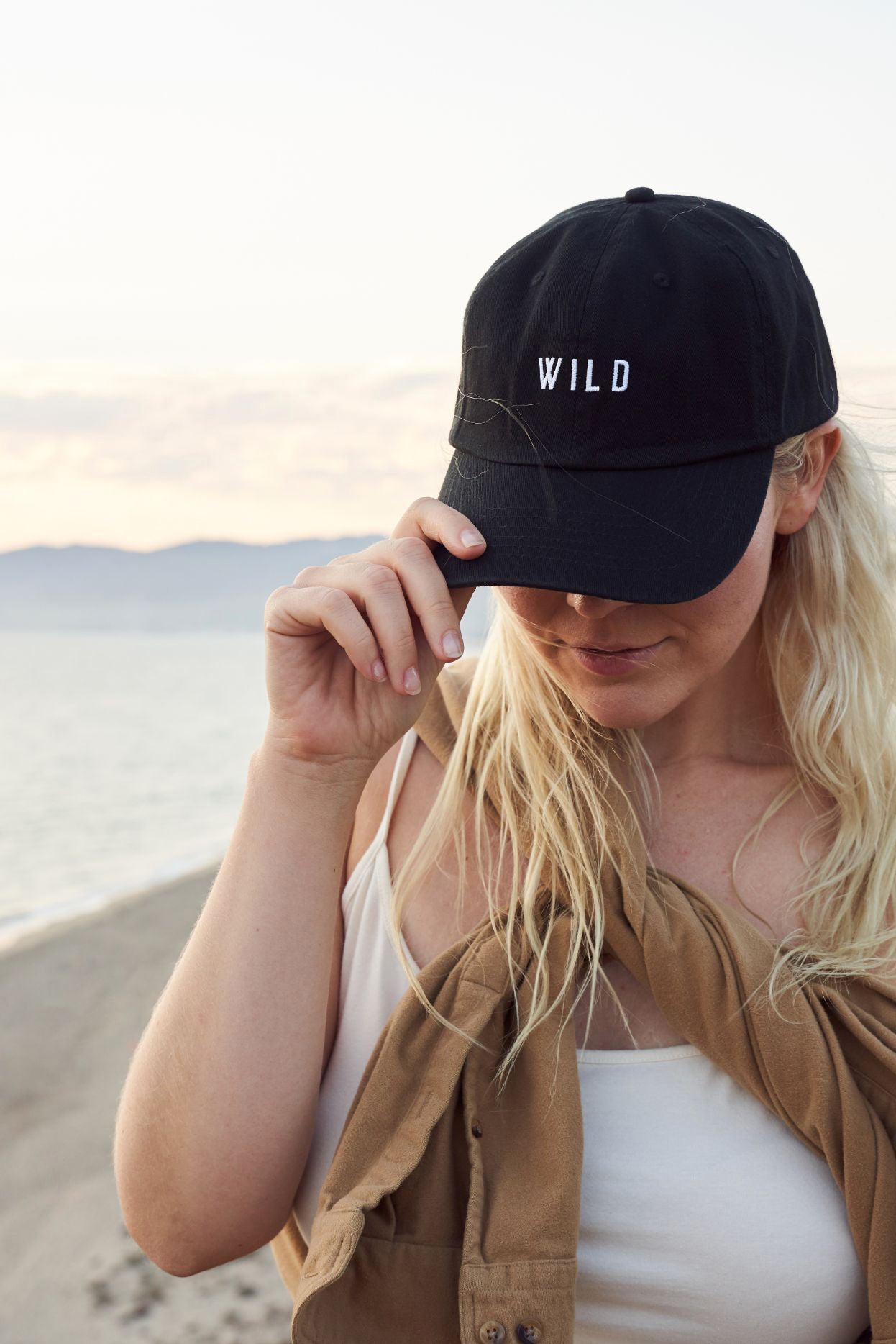 woman at beach with black dad hat #color_black