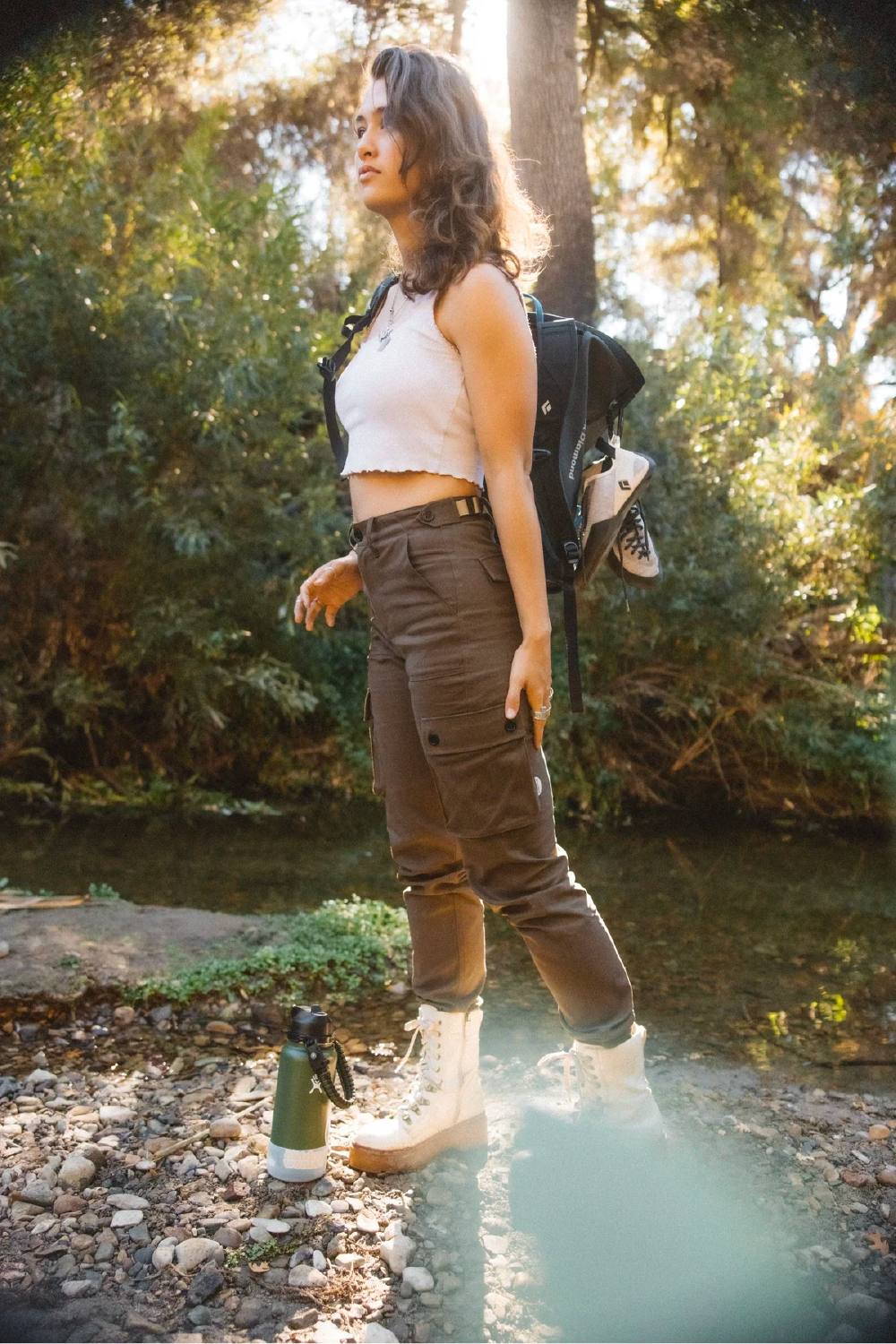 woman in khaki brown cargo outdoor hiking camping pants in forest and crop tank top #color_brew