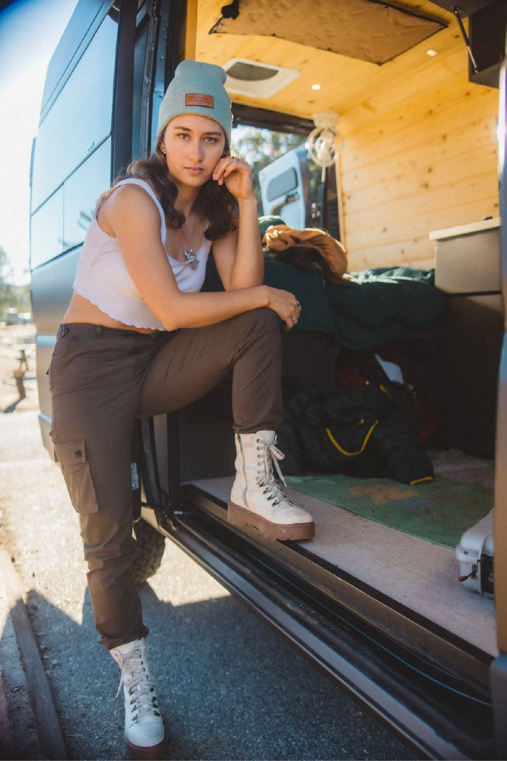 woman in khaki brown cargo outdoor hiking camping pants in travel van and crop tank top #color_brew