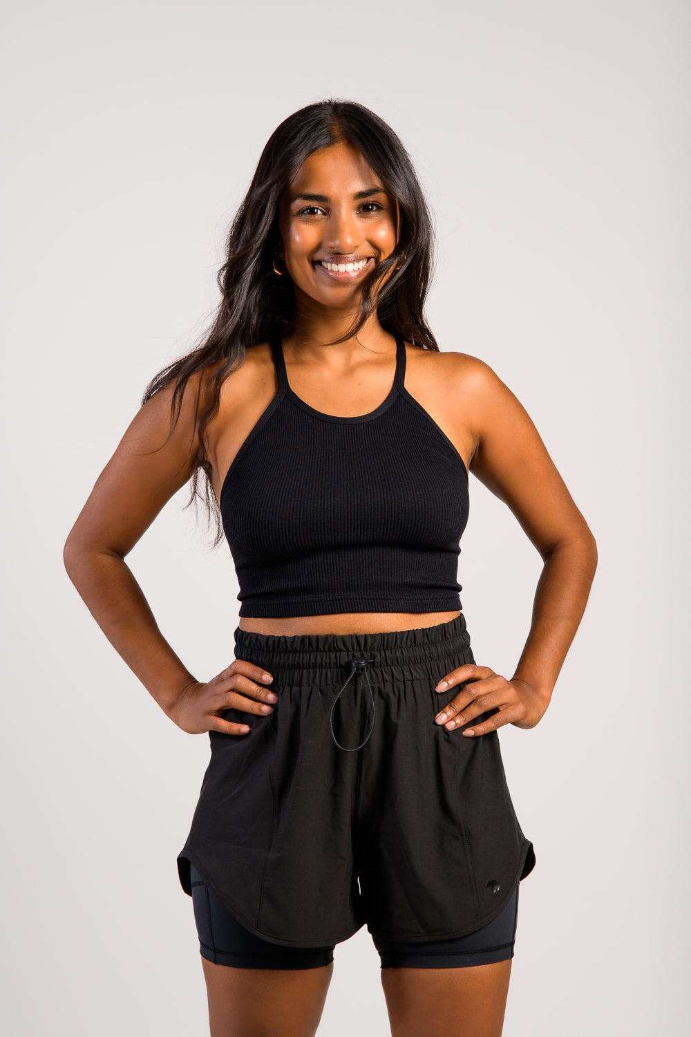 brown woman in black workout running track shorts with tank top #color_black