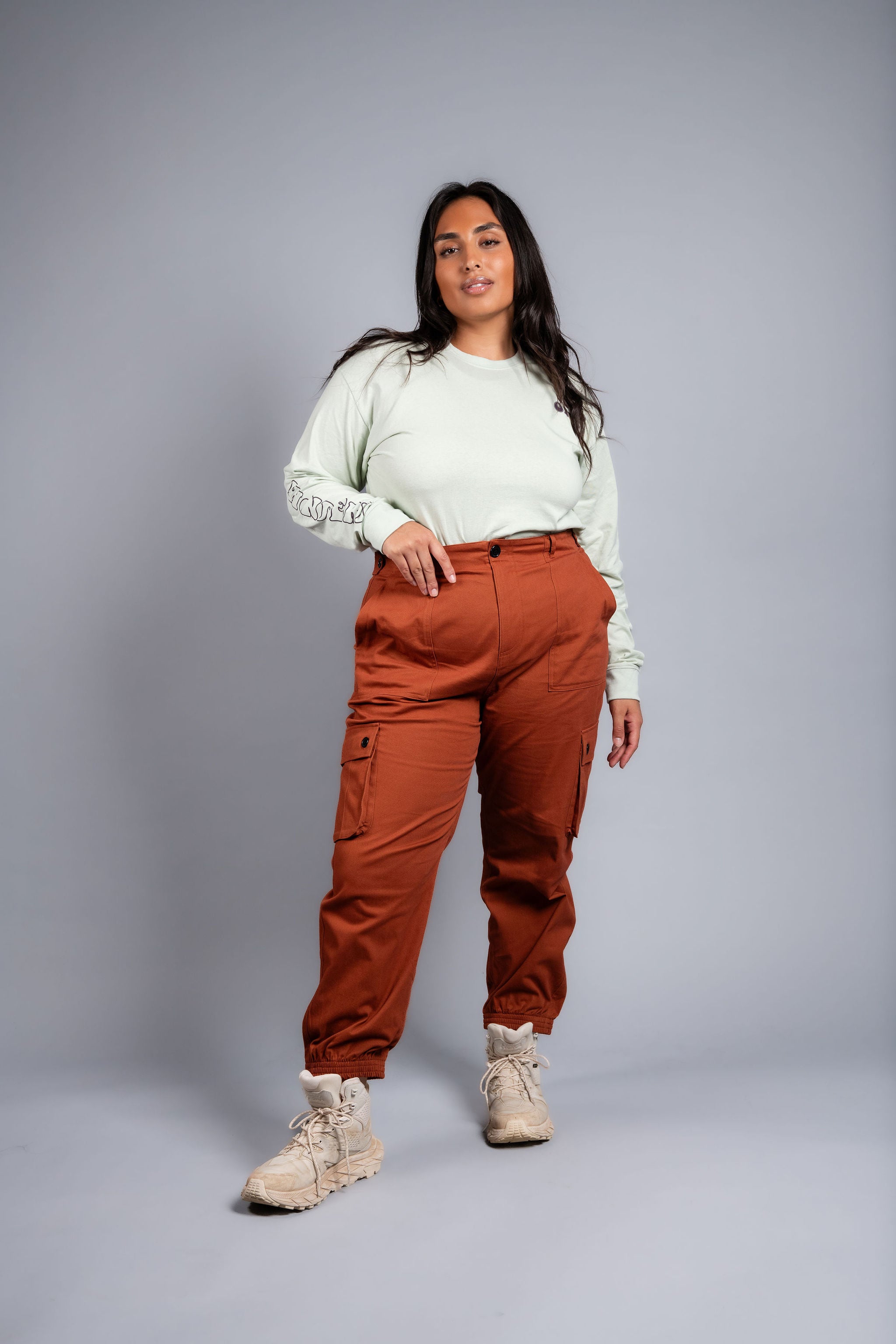 woman in adjustable orange cargo hiking pants and long sleeve top #color_burnt Sienna