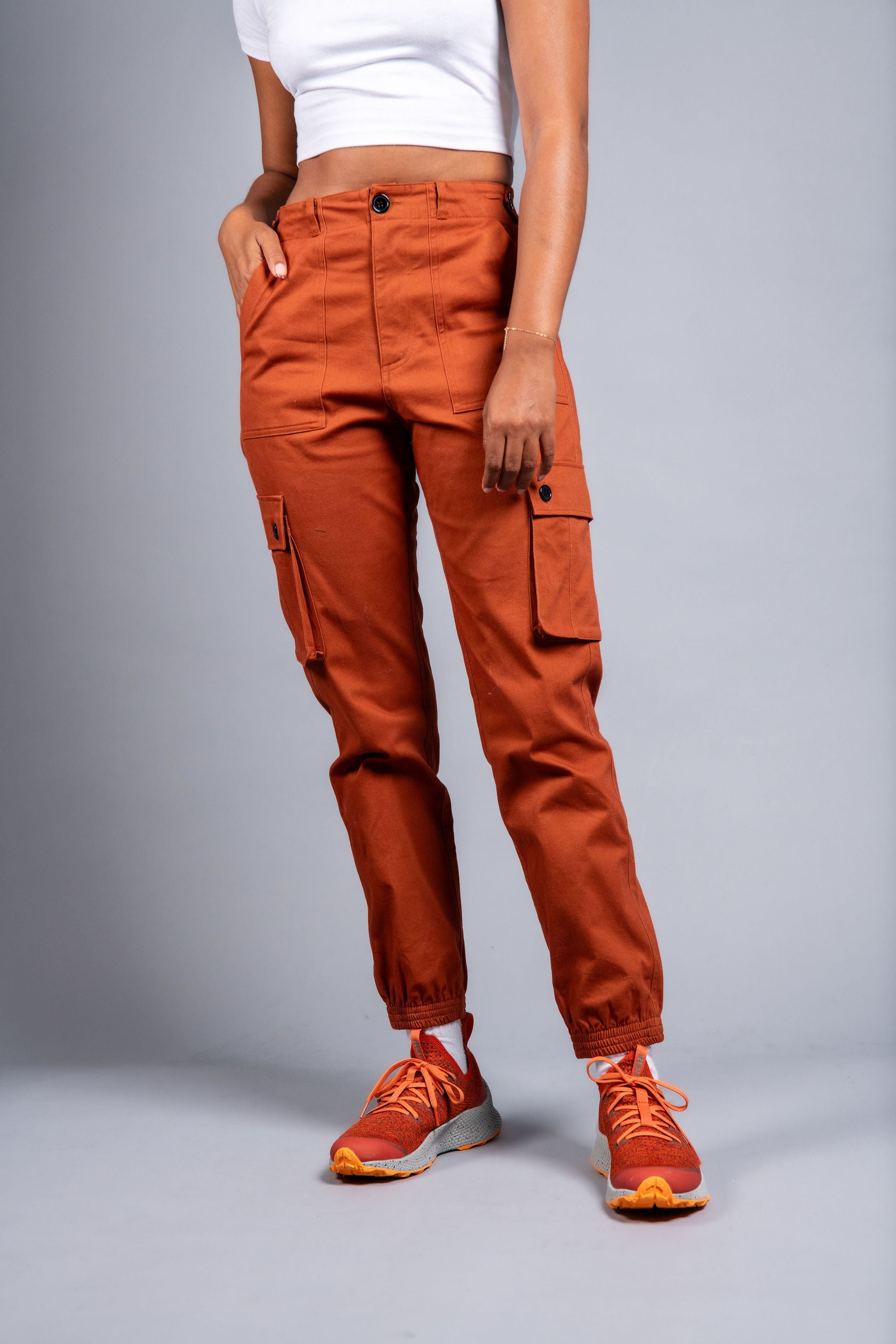 woman in adjustable orange cargo hiking pants and tee shirt #color_burnt Sienna