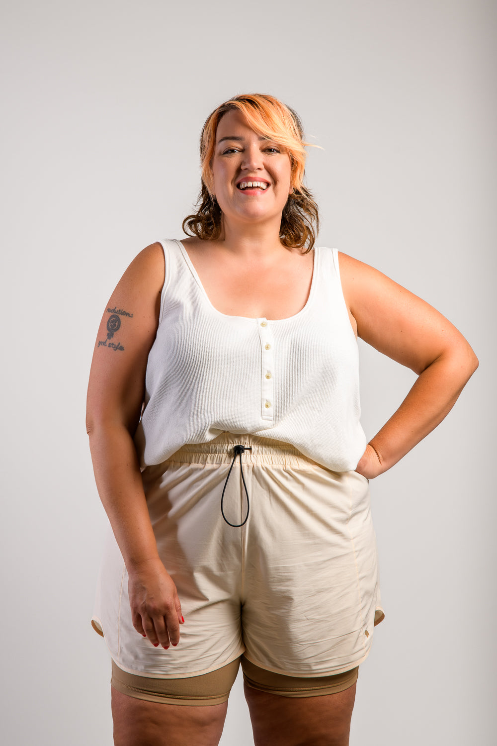 plus size woman in cream lightweight running shorts and biker shorts with side pocket #color_cream/Sand