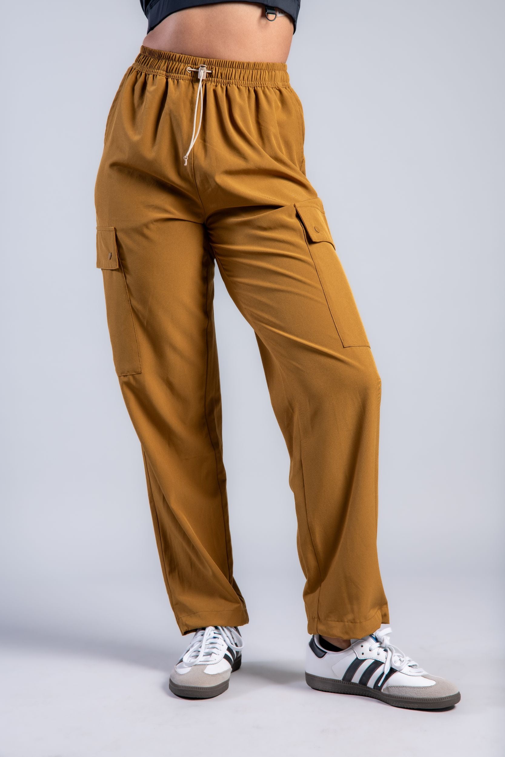 woman stretching in brown lounge cargo pants brown woman in black tank top and brown loose lounge pants and adidas #color_ochre