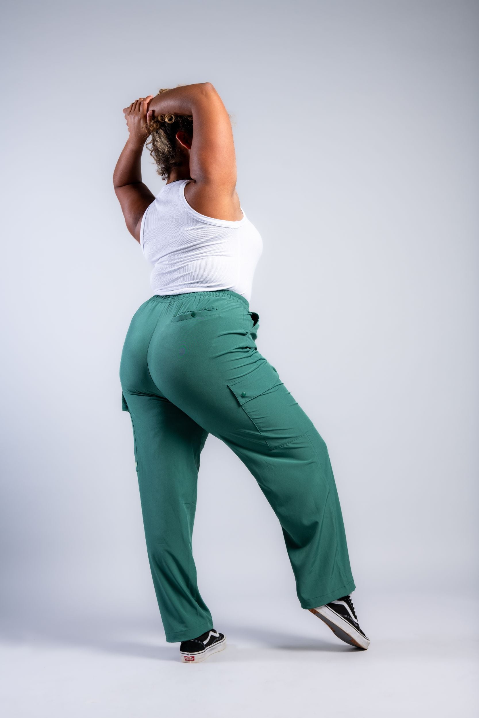 Tall woman stretching in white tank top and green loose lounge pants #color_sagebrush