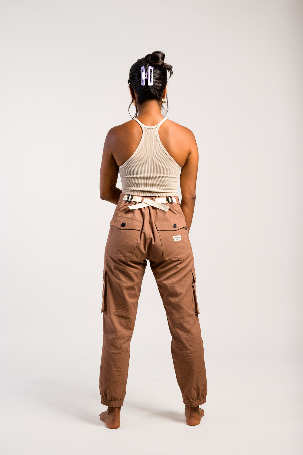 petite woman in adjustable brown cargo hiking pants and tank top #color_umber